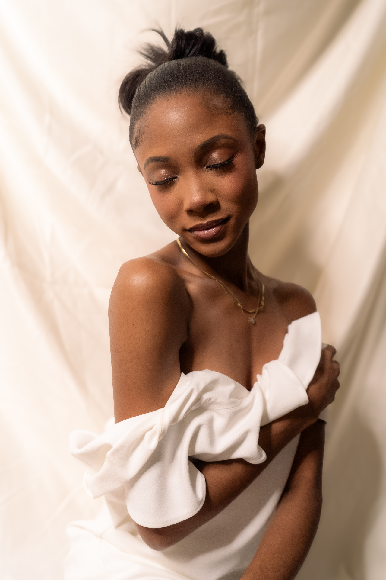 Studio portrait of Chelsey Moné wrapped in cream fabric against a seamless backdrop