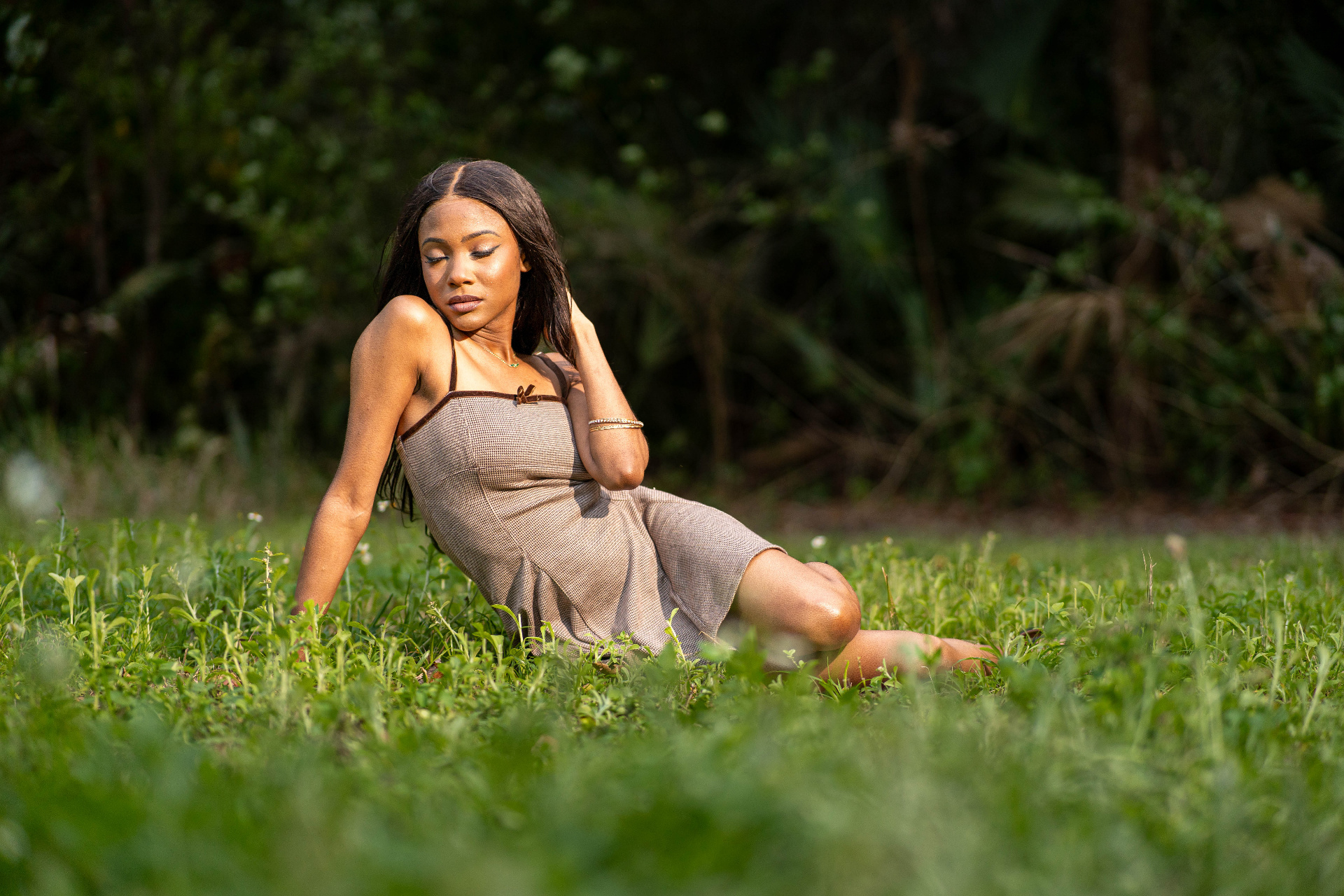 Lifestyle frame of Chelsey Moné seated in tall grass at golden hour in a linen dress