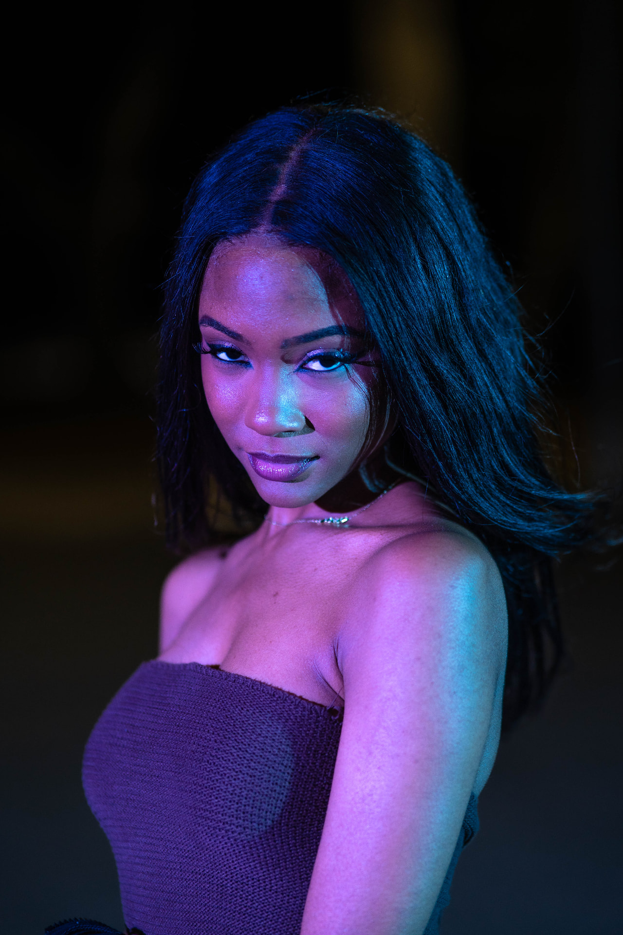 Cinematic blue and magenta neon-lit night portrait of Chelsey Moné looking over her shoulder